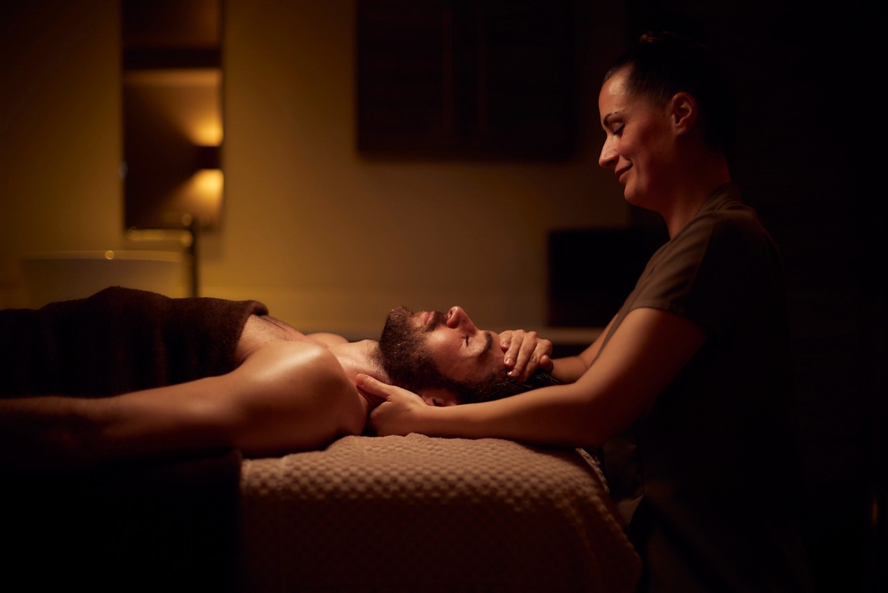 Spa therapist giving a man a relaxing facial treatment.
